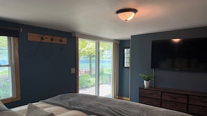 Un dormitorio con cama, televisor, ventana y vistas al exterior.
