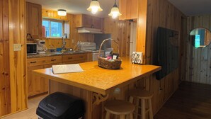 Una cocina con armarios de madera, microondas, cafetera e isla de madera con taburetes.