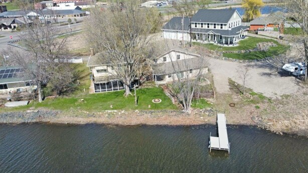Una propiedad junto al lago con una casa grande, un muelle y un césped bien cuidado.