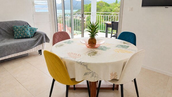 A dining area with a round table, chairs, and a pineapple centerpiece. - Horizon Caraïbes – Panoramic View over the Bay of Sainte-Anne (Sainte-Anne)