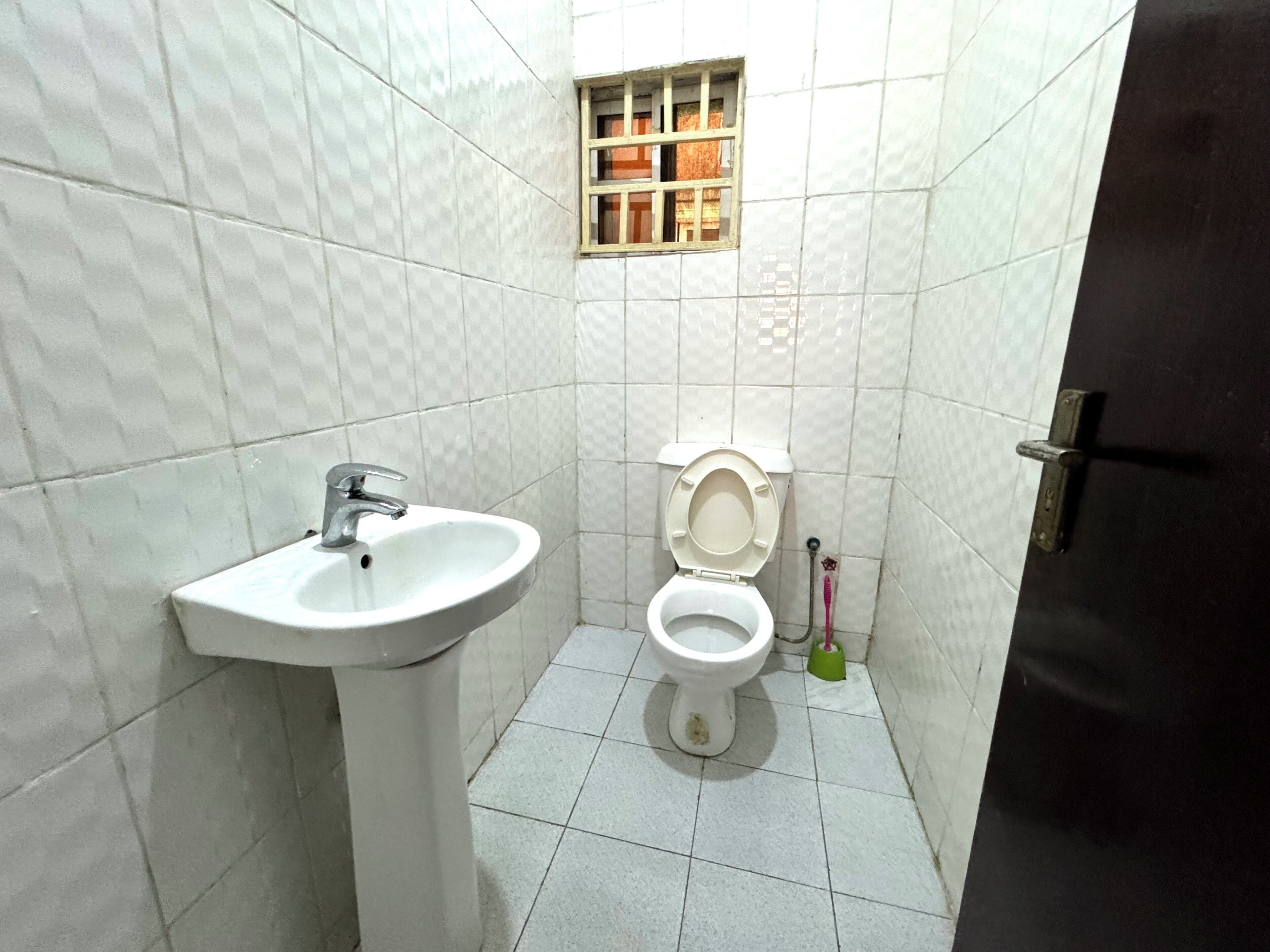 A small bathroom with a white sink, a toilet, and a window.