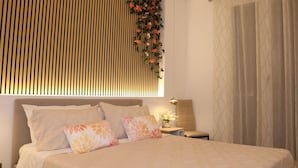 A bedroom with a bed, pillows, a nightstand, a lamp, a wall-mounted plant, and a window with curtains. - Alumaro House (Castellammare del Golfo)