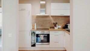 Una cocina compacta con armarios blancos, horno empotrado y encimera de madera.