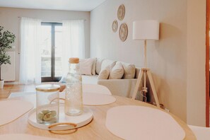 A modern living room with a sofa, a table with decorative items, a lamp, and a view through a glass door. - ApartmentTraveller Saarlouis near city center (Saarlouis)