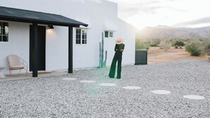 Un edificio moderno blanco con camino de grava y un cactus al fondo.