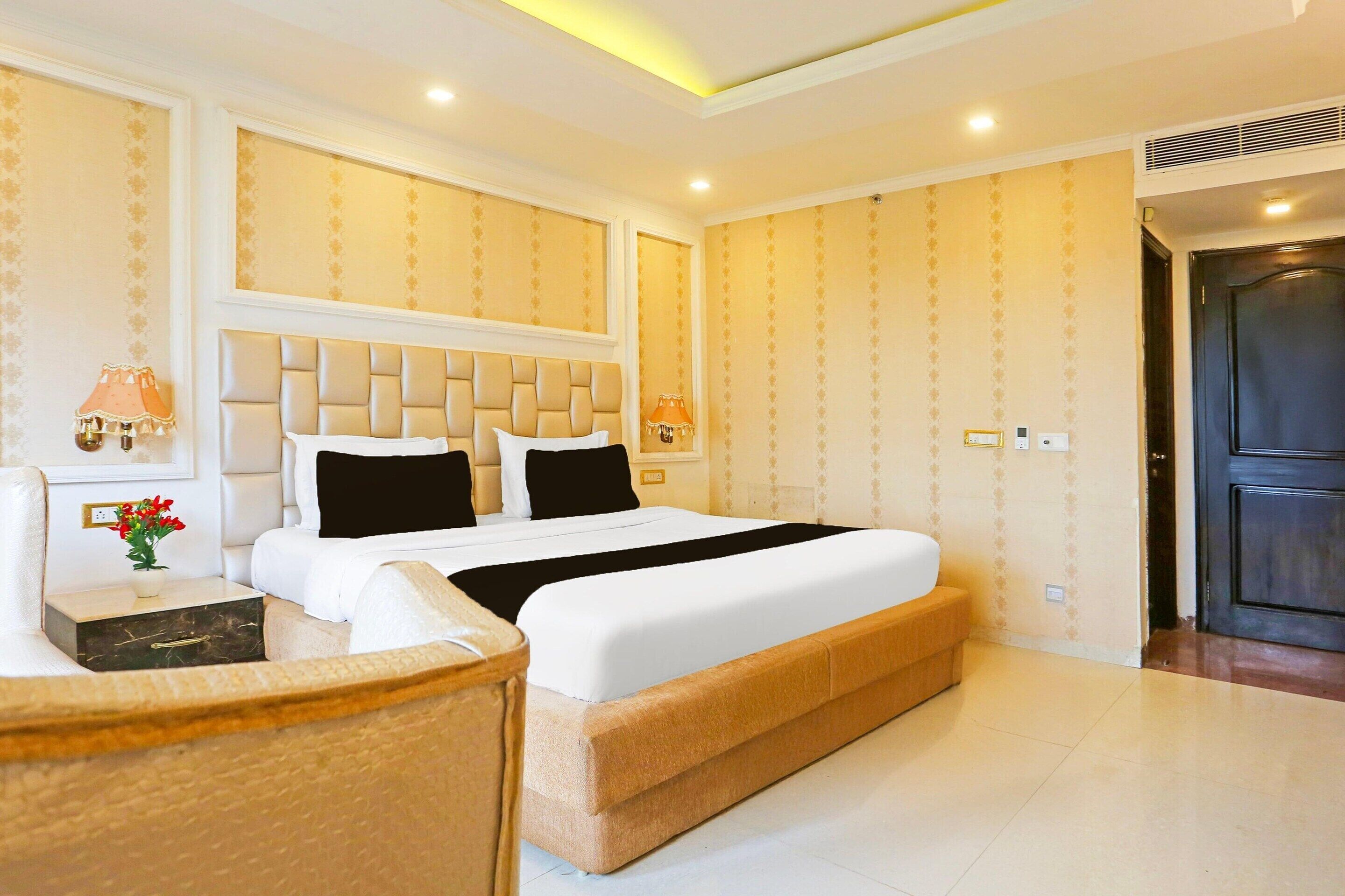 Ein Hotelzimmer mit einem großen Bett, einem Nachttisch mit Lampe, einem kleinen Tisch mit Blumen und einem Sessel.