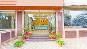 A hotel entrance with a checkered floor, potted plants, and a sign reading "Resort". - Stylish Room With Mesmerizing View Dharamshala (Dharamshala)