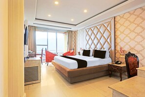 Habitación de hotel con una cama grande, un escritorio, una silla y una ventana con cortinas.