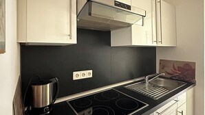 A modern kitchen with a black countertop, stainless steel stove, and white cabinets.