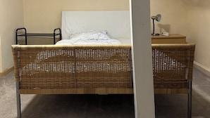 A single-walled room with a bed, a desk, and a skylight.