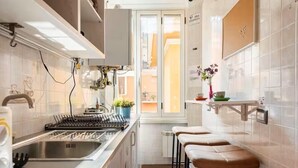 Eine moderne Küche mit Einbauherd, Spüle und Fenster mit Blick auf einen Balkon.