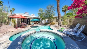Ein Garten mit Swimmingpool, Liegestühlen und einer überdachten Terrasse.
