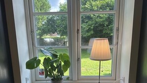 Ein Essbereich mit einem Tisch für zwei Personen, einem Blumentopf und einer Lampe auf einem Fensterbrett.
