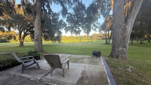 Un patio con dos sillas Adirondack y una parrilla.
