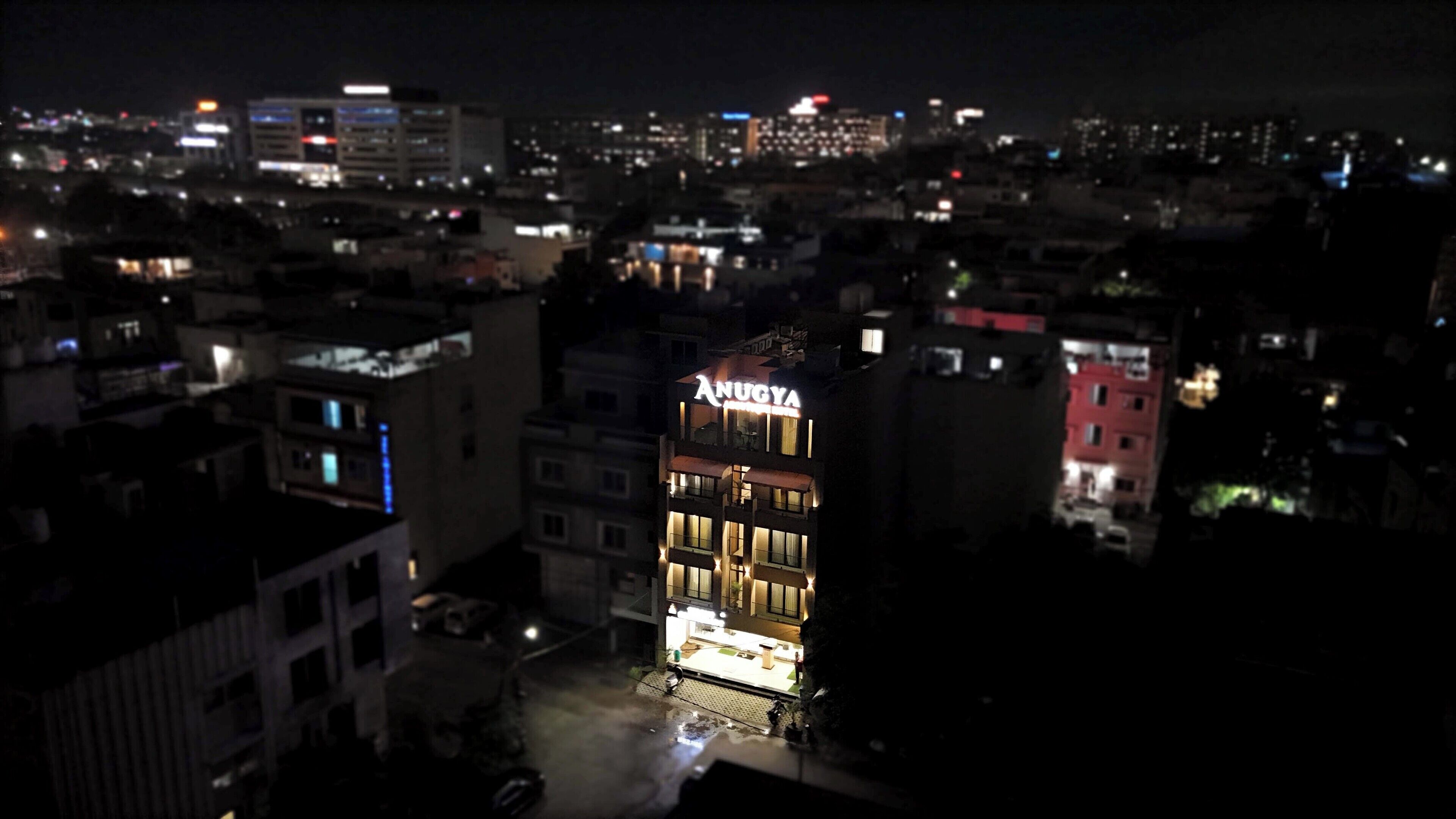 A multi-story hotel with illuminated signage, surrounded by a cityscape at night.
