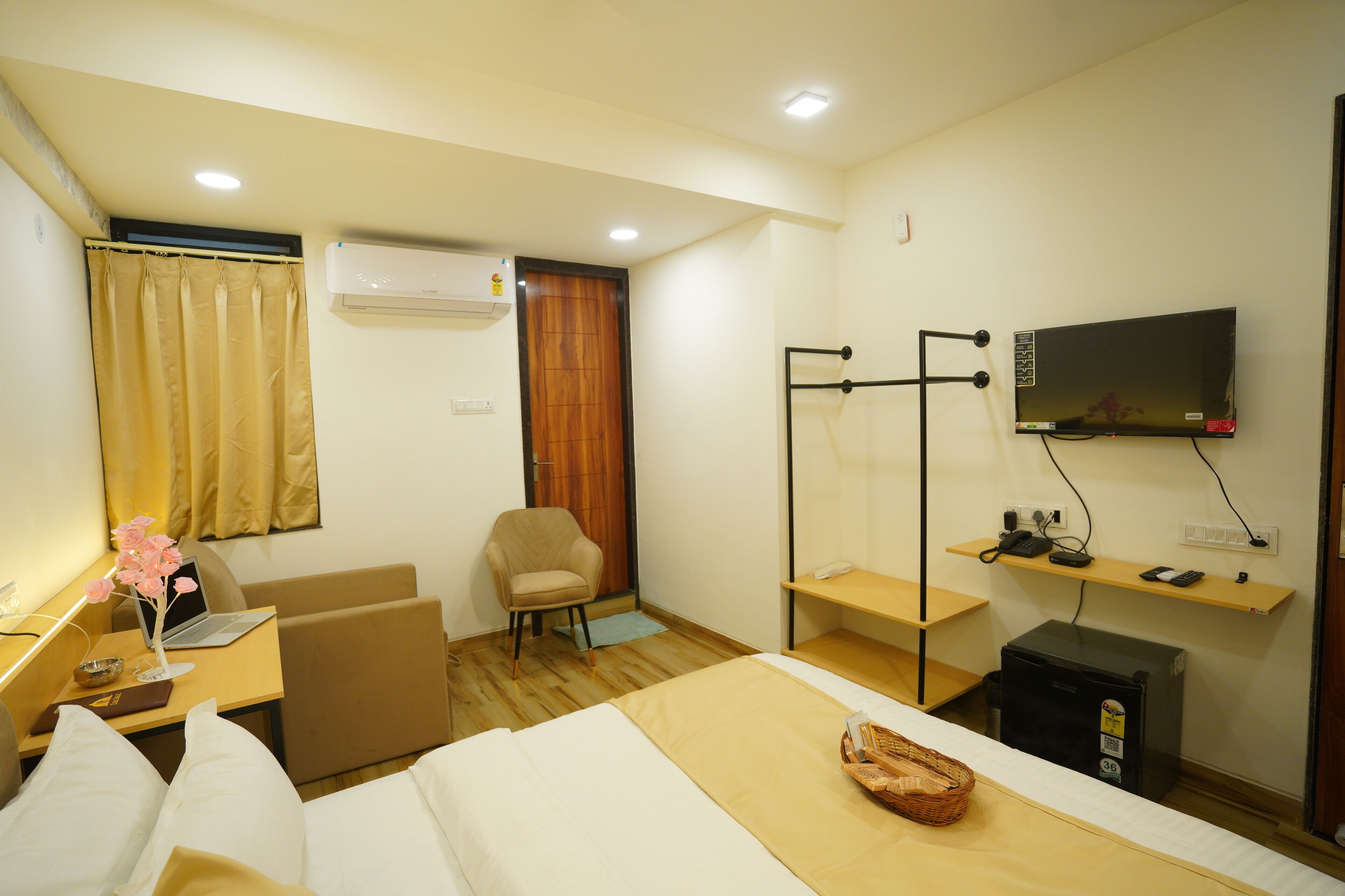 Une chambre d’hôtel équipée d’un lit, d’un bureau avec un ordinateur portable, d’une chaise, d’un téléviseur fixé au mur et d’un appareil de climatisation.