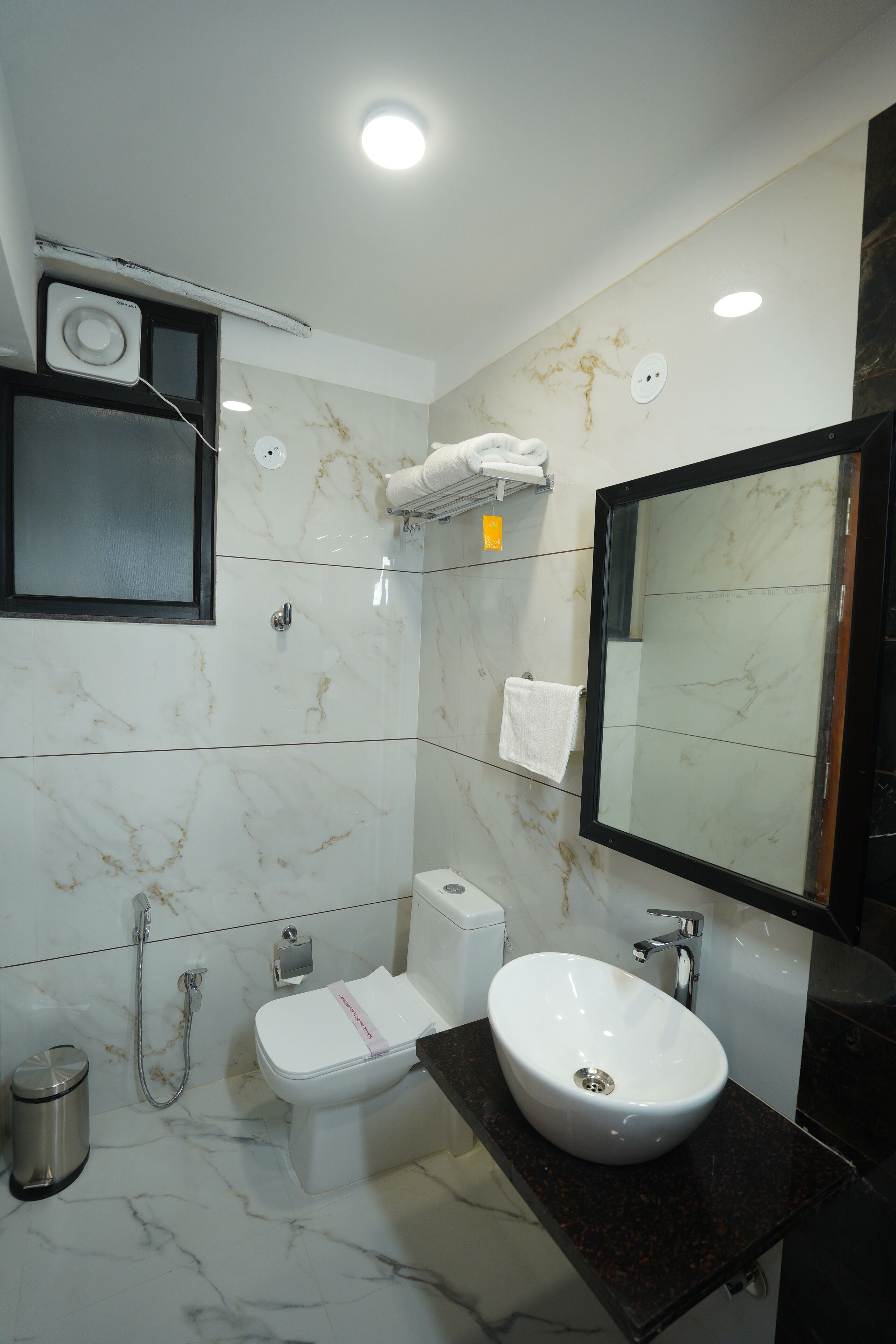A bathroom with a white toilet, a sink, a mirror, and a shower.