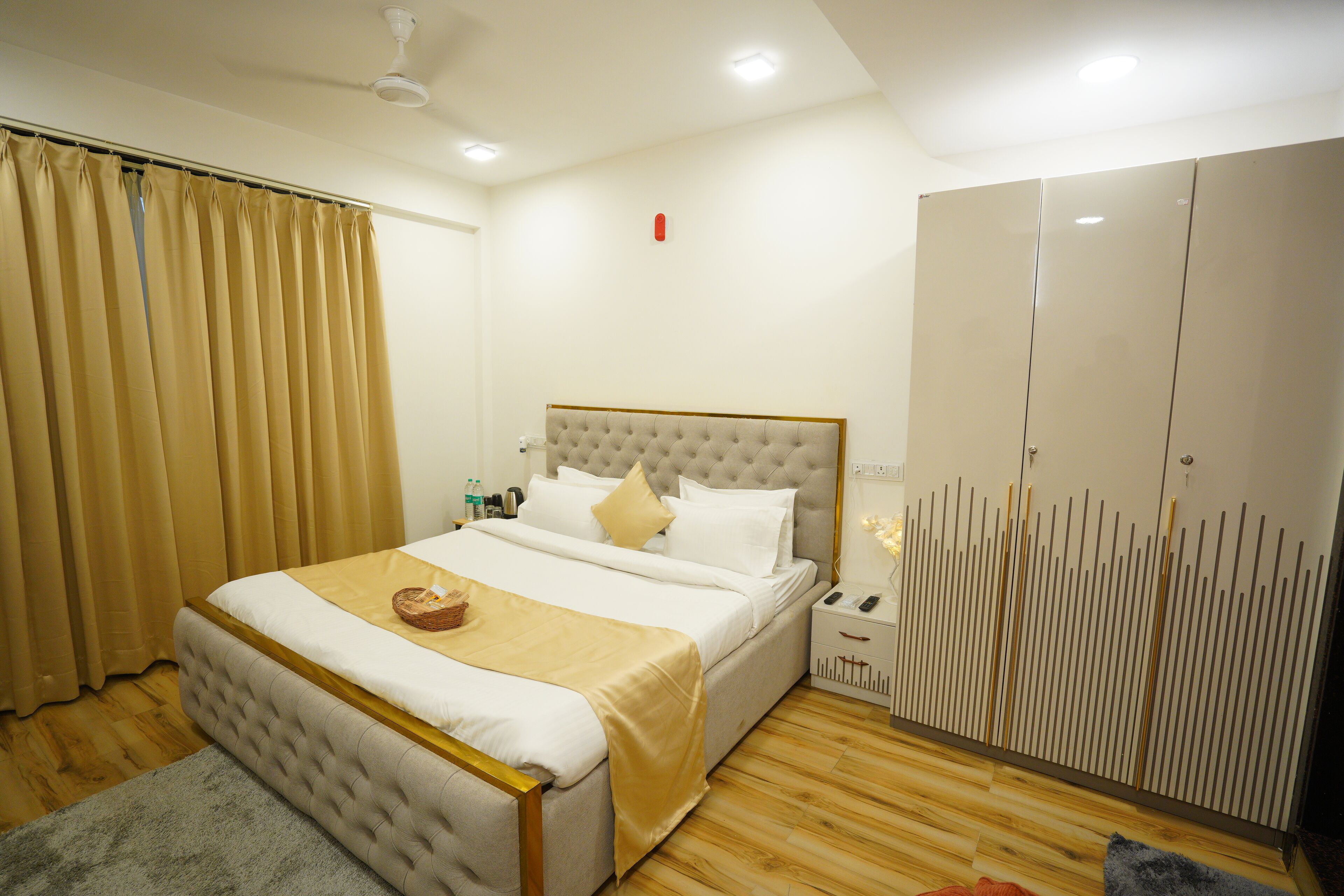 Un dormitorio ordenado con una cama grande, una mesita de noche, un armario y un ventilador de techo.
