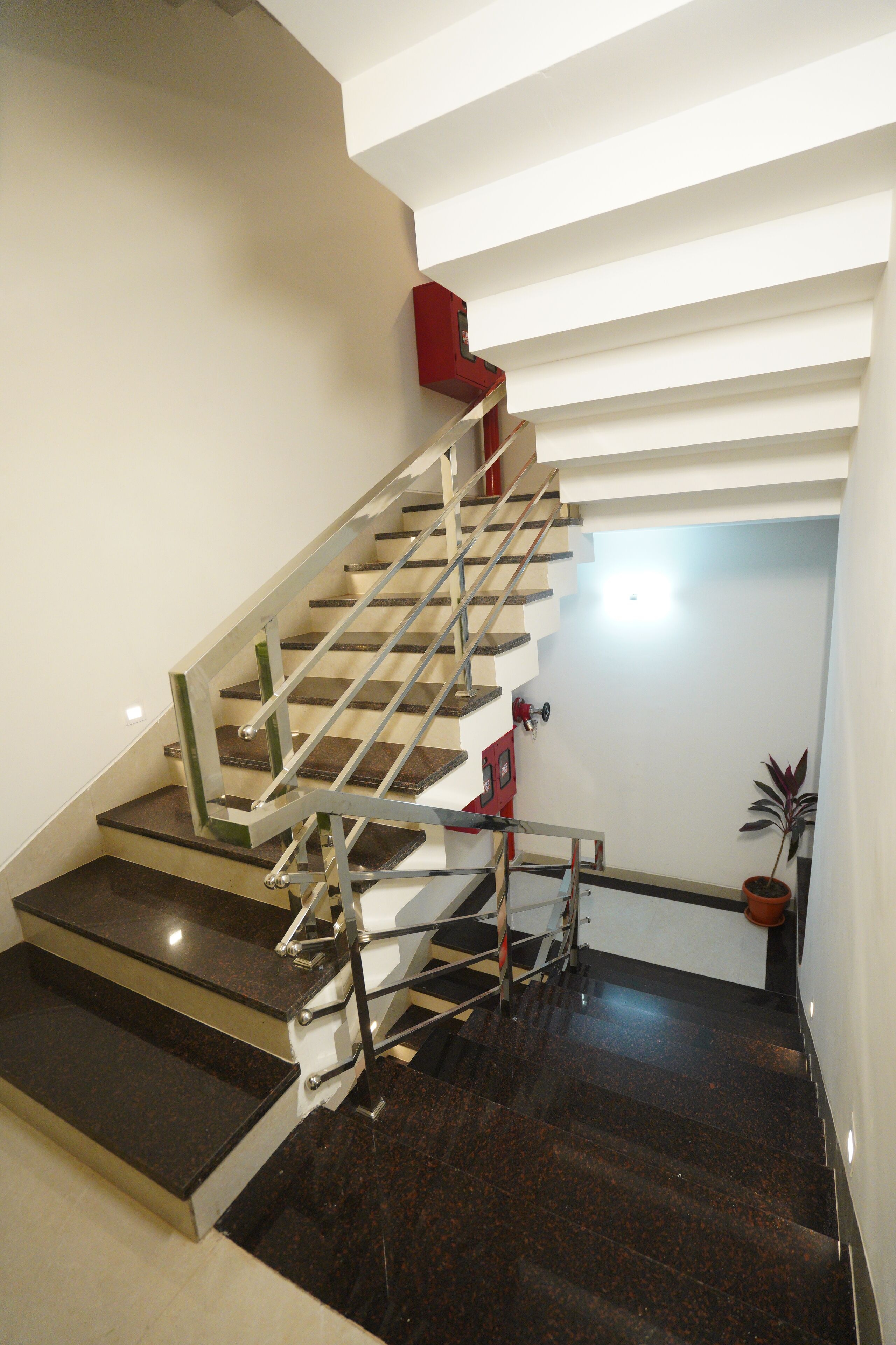 Una escalera moderna con barandillas de metal y escalones de mármol oscuro que conducen a una plataforma.