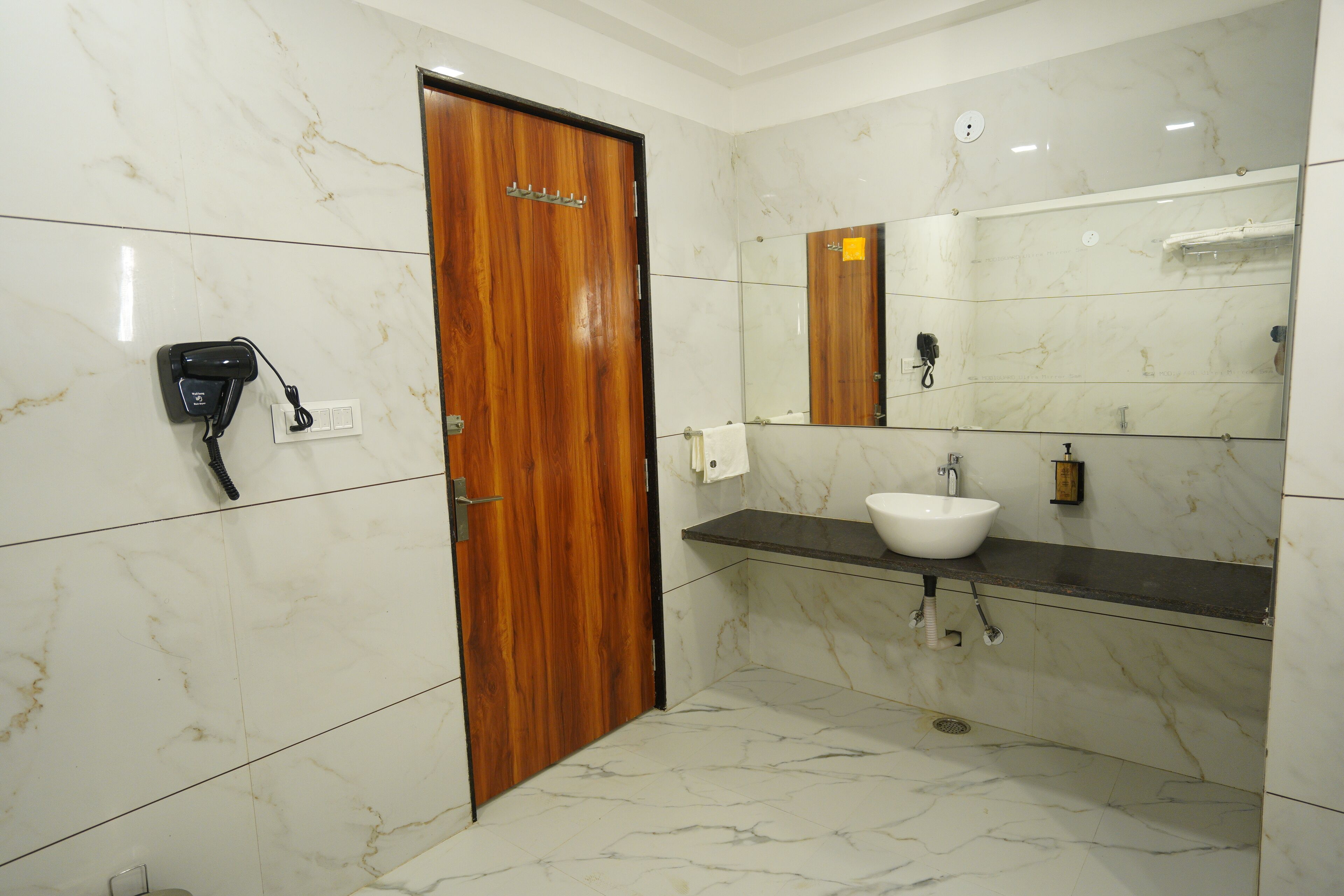 A bathroom with a wooden door, a white sink, and a mirror above it.