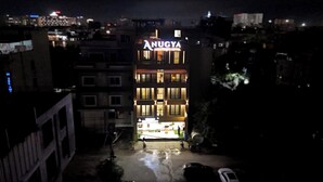 A hotel named "Anugya" with a modern design, featuring multiple floors and illuminated windows. - Anugya - A Boutique Hotel (Indore)