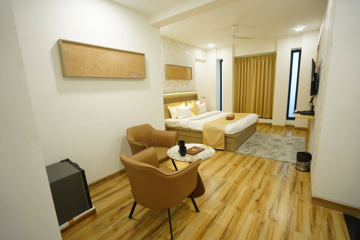 Habitación de hotel con cama, escritorio, silla y televisor.