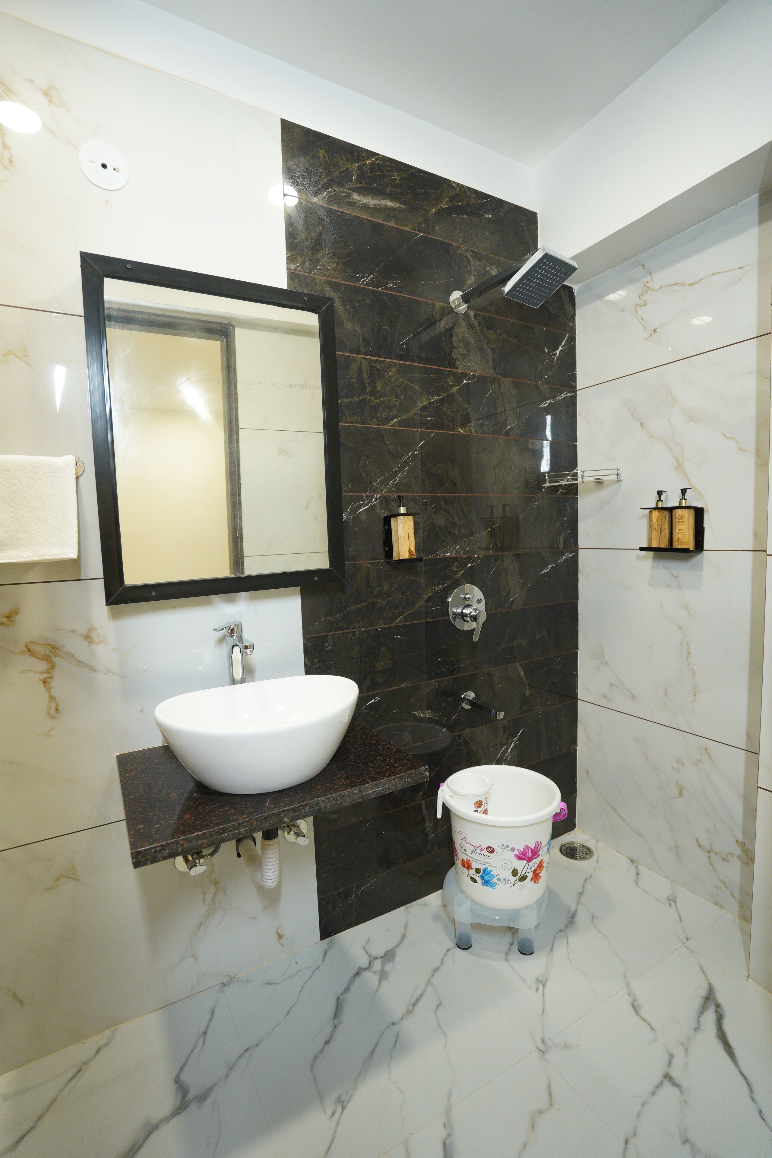 Egy modern fürőszoba, melyben fehér mosdókagyló, tükör, zuhanyzó és WC található.