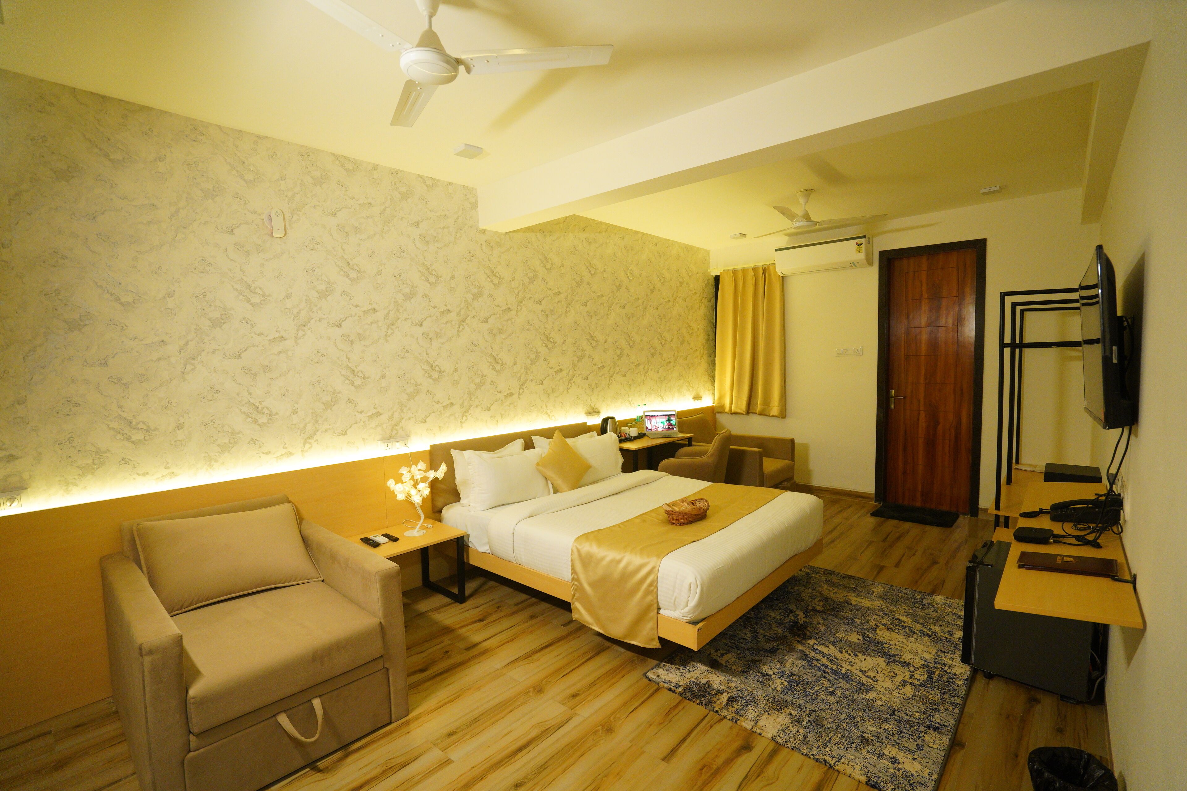 A hotel room with a bed, a desk, a chair, a TV, and a ceiling fan.