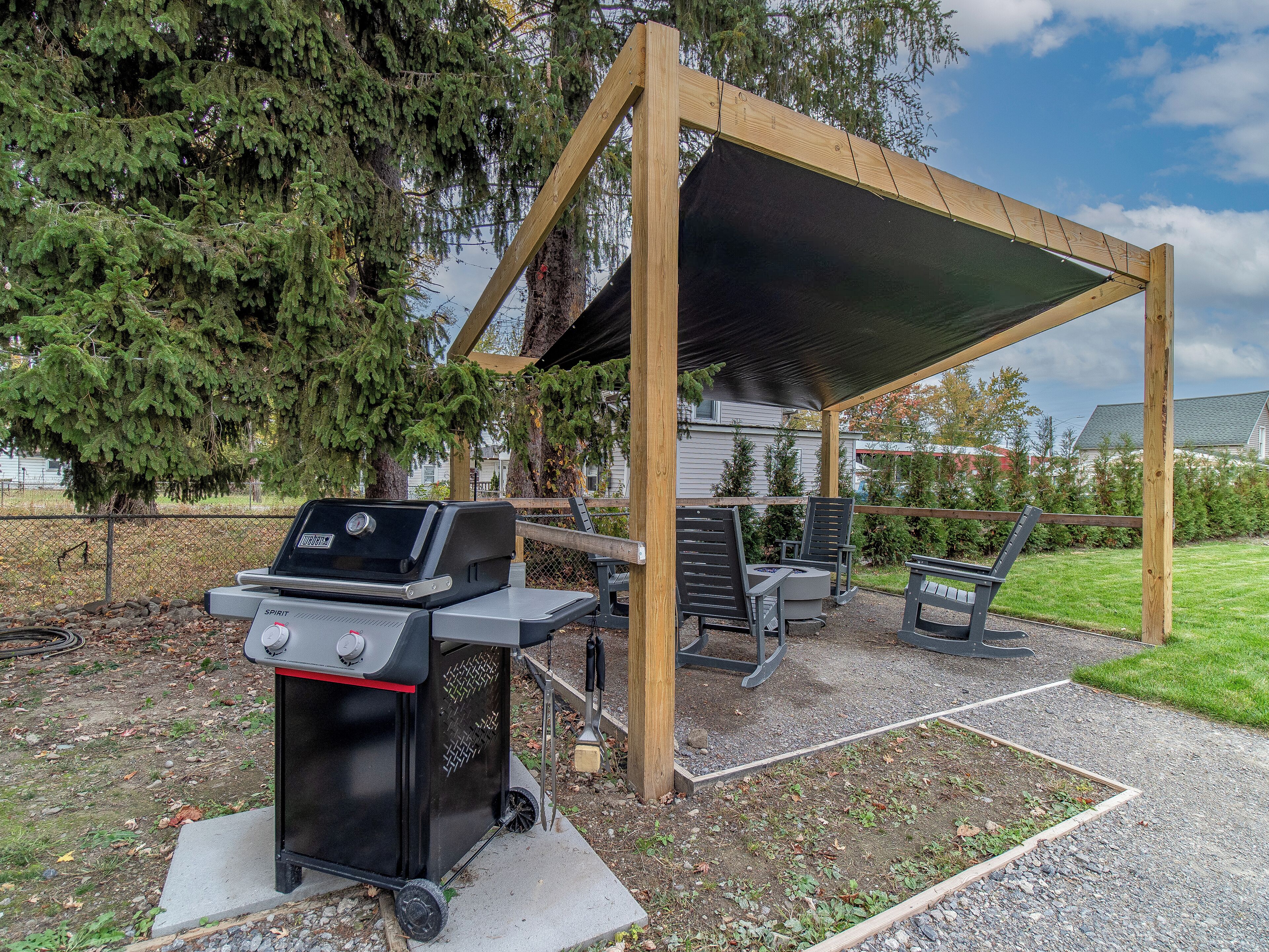 A covered outdoor area with a grill and seating.