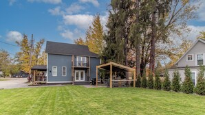 A two-story house with a covered patio and a well-maintained lawn. - The Refined Retreat (Celoron)