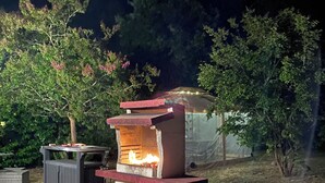 An outdoor grill setup with a fire burning, surrounded by a patio area with tiled flooring and a small table. - Spacious family home on the Arcachon basin (La Teste-de-Buch)