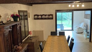 A dining area with a long wooden table, black chairs, a wooden cabinet, and a wall-mounted shelf with decorative plates. - Spacious family home on the Arcachon basin (La Teste-de-Buch)
