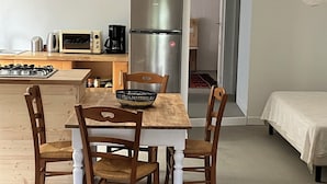Een kleine woonruimte met een eethoek, kitchenette en een bed.