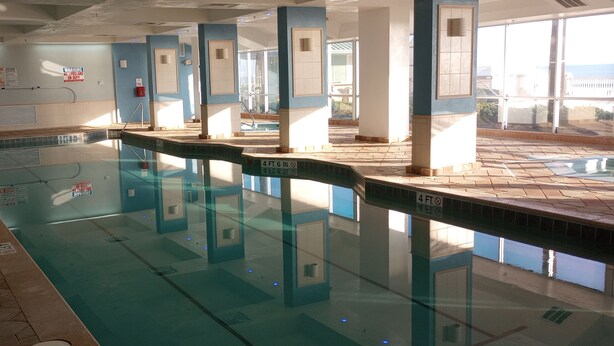 Une piscine intérieure à l’eau claire, avec des murs et un sol carrelés.