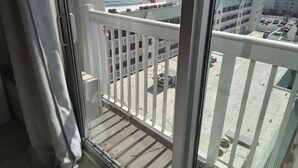 Un balcon avec vue sur l’océan et un parking.