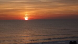 Un coucher de soleil sur une mer calme, avec un horizon dégagé.
