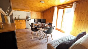 Un intérieur de chalet chaleureux comprenant un coin repas, une cuisine et un canapé.
