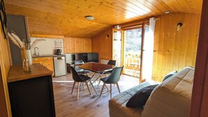 Un chalet confortable avec un intérieur en bois, un coin repas avec une table et des chaises, et un canapé.