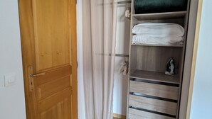 Une pièce avec une porte en bois, un placard avec des étagères et un rideau.