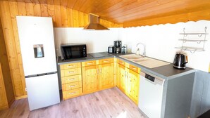 Une cuisine compacte dotée de meubles en bois, d’un four à micro-ondes, d’une machine à café, d’une bouilloire et d’un évier.