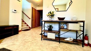 A hallway with a wooden console table, a hexagonal mirror, and a fire extinguisher. - Charming Family Friendly House, Hot tub, Playroom (Long Pond)