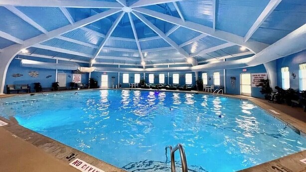 An indoor swimming pool with a high ceiling and a blue color scheme. - Charming Family Friendly House, Hot tub, Playroom (Long Pond)