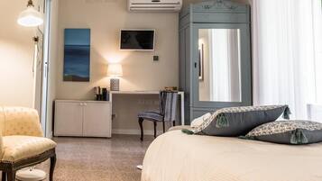 Ein Hotelzimmer mit Bett, Schreibtisch, Stuhl, Kleiderschrank, Fernseher und einem Bild an der Wand.