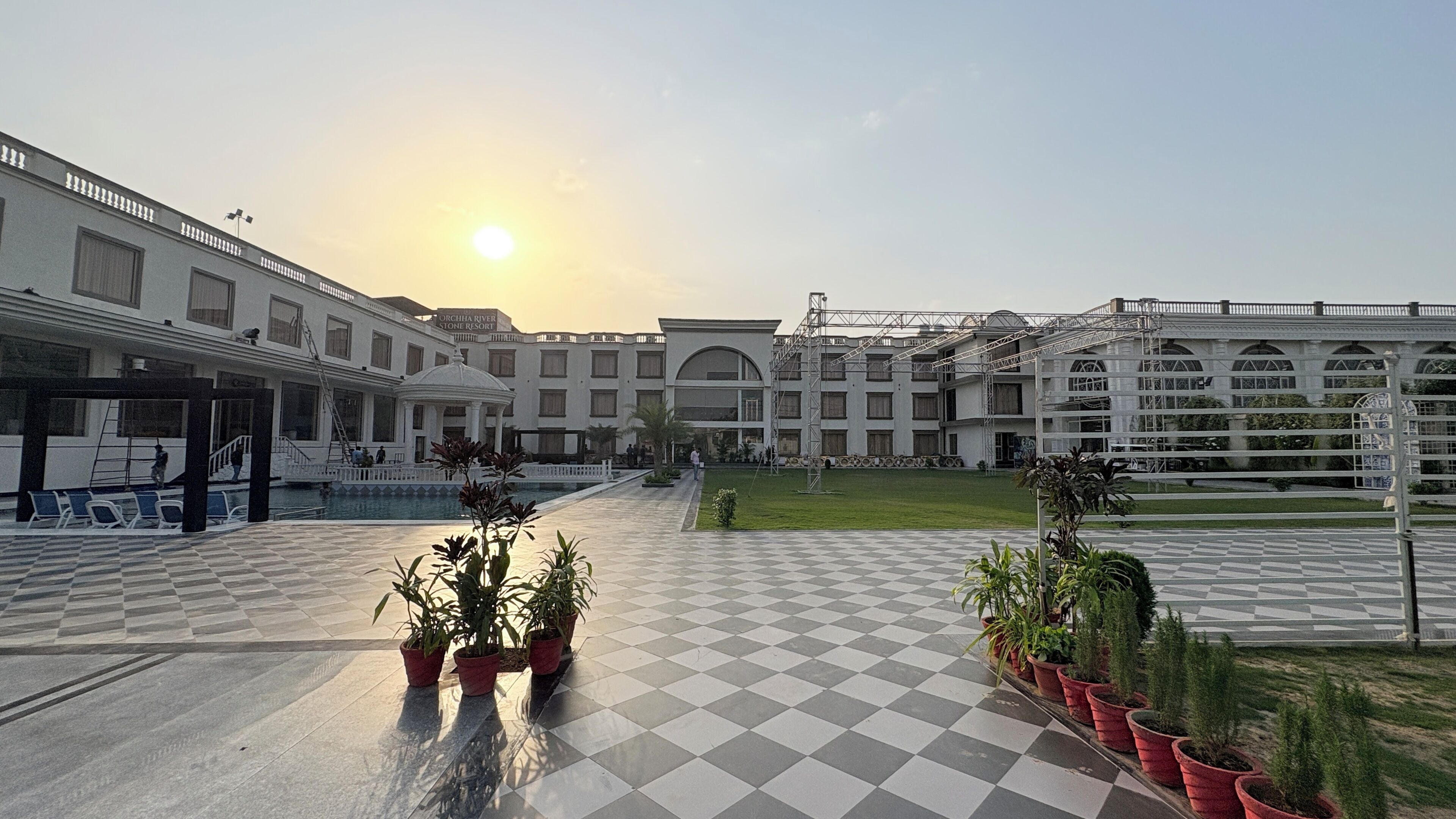 A hotel courtyard with a pool, potted plants, and a checkered floor.