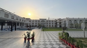 A hotel courtyard with a pool, potted plants, and a checkered floor.