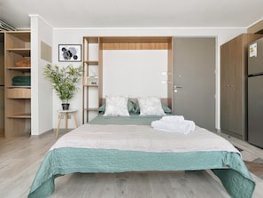 A modern bedroom with a bed, a potted plant, a radio, and a wardrobe. - Oceana Suites Carmen (Santiago)