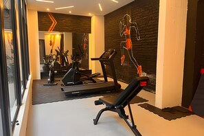 A gym with treadmills, a bench, and a wall-mounted sculpture.