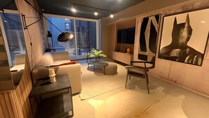 Ein modernes Wohnzimmer mit einer Couch, einem Couchtisch und einem Sessel. Ein großes Fenster bietet Blick auf die Stadt.