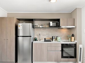 A modern kitchen with a stainless steel refrigerator, a microwave, a built-in oven, and a dishwasher.