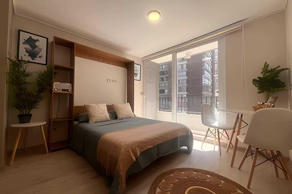 A modern bedroom with a bed, bedside tables, a desk, and a chair.